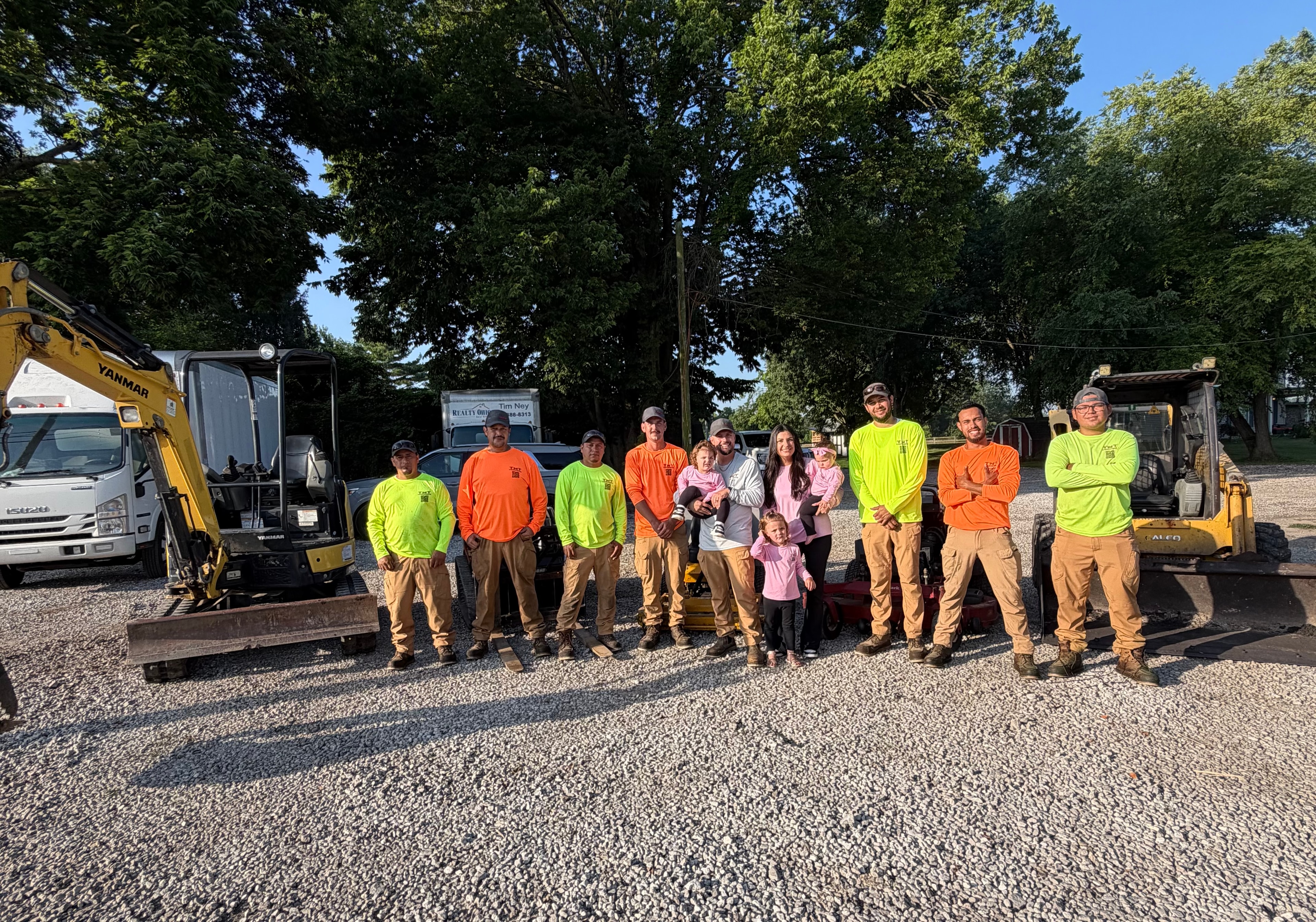 A group of workers posing in front of vehicles.